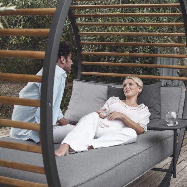 Image of man and woman relaxing with Cradle Lounge minimalist cabana daybed by Gloster