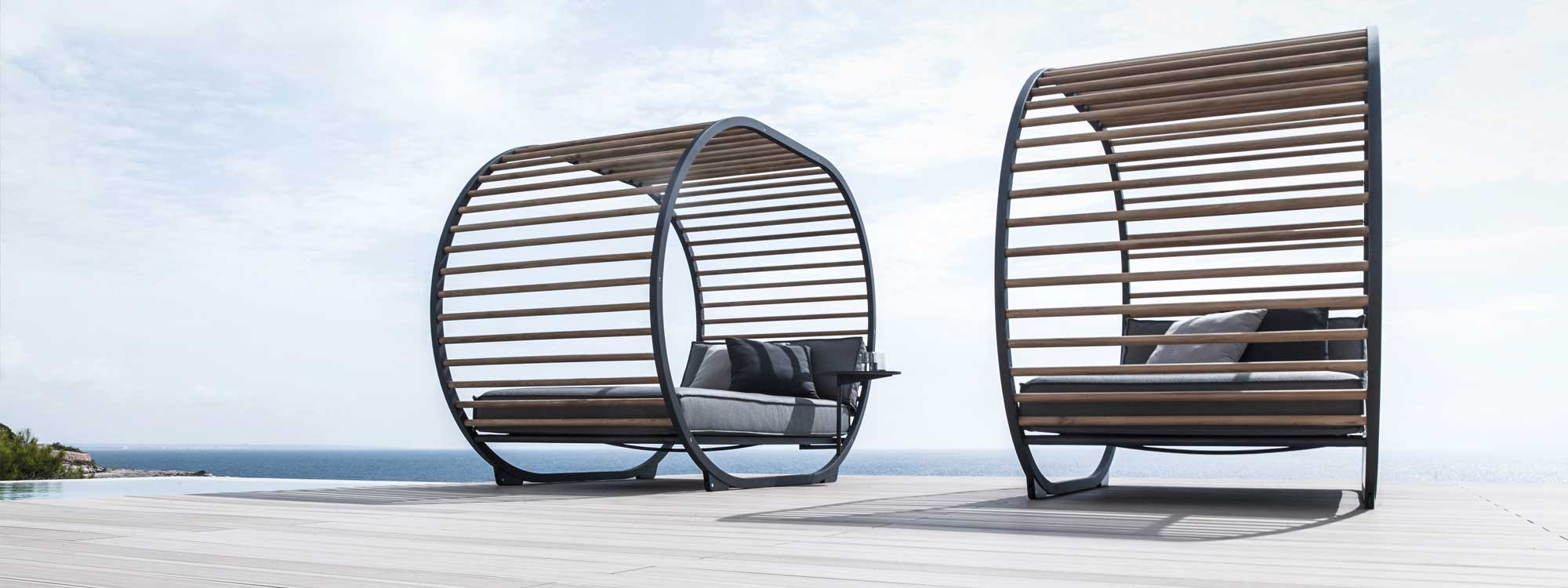 Image of pair of Gloster Cradle Lounge garden daybeds on terrace with blue sea and sky in the background