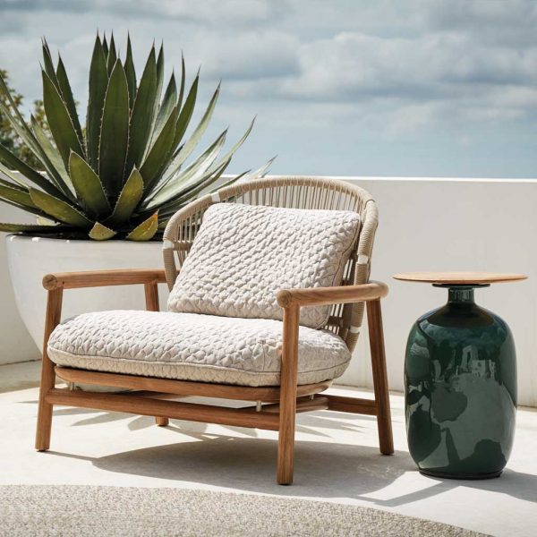 Image of Gloster Fern low back garden lounge chair in teak with white all-weather rope and cushions, next to Blow side table