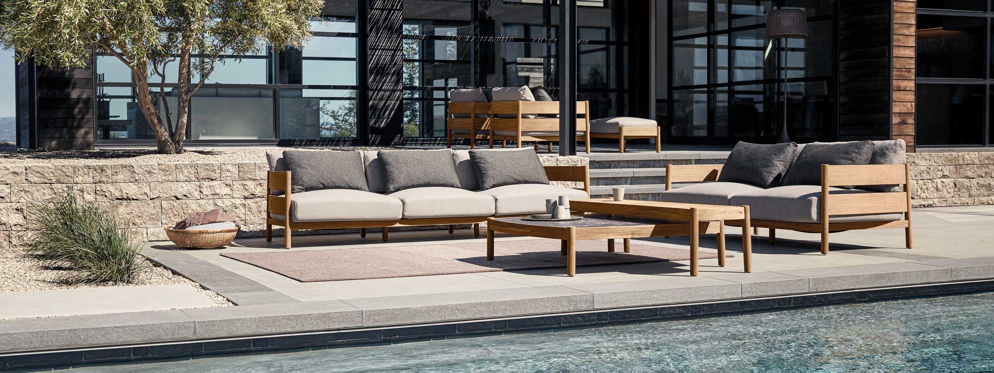 Image of Gloster Haven modern teak garden sofas on tiered terraces with elegant modern house in the immediate background
