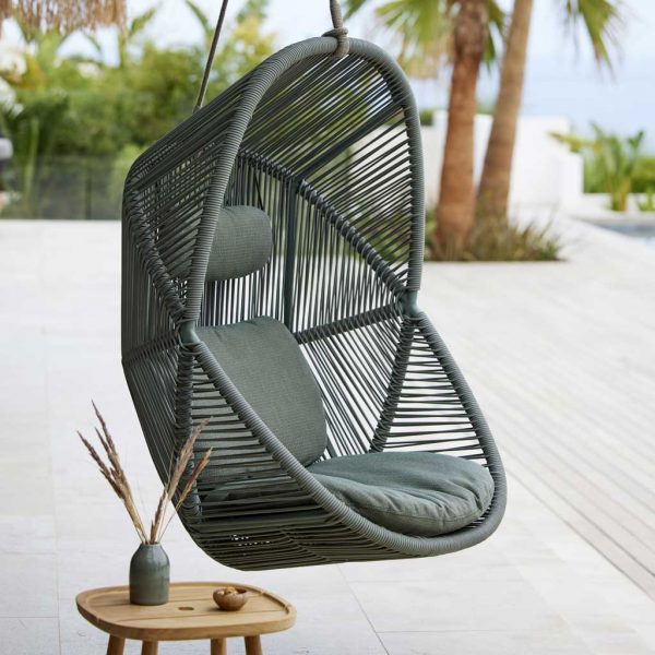 Image of Cane-line Hive modern swing chair in Dusty Green Cane-line Weave next to Royal Teak low table