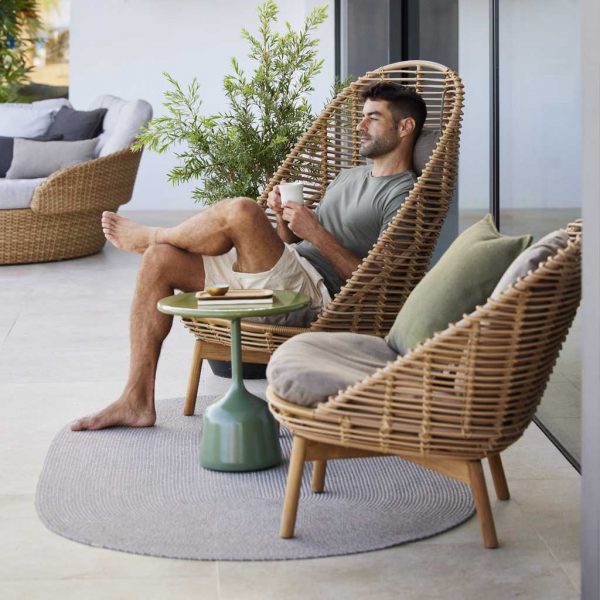 Image of man sat drinking a cup of coffee whilst sat in Hive modern wicker garden chair by Cane-line
