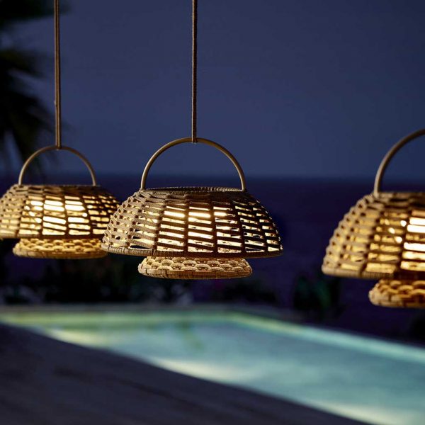 Image of row of Cane-line Illusion solar LED lanterns in taupe SoftRope with illuminated swimming pool in the background