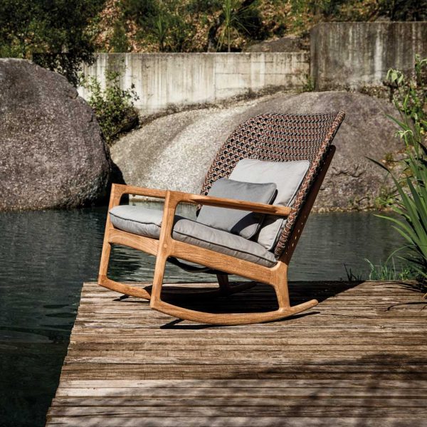 Image of Gloster Kay wicker rocking chair on wooden decking next to water feature