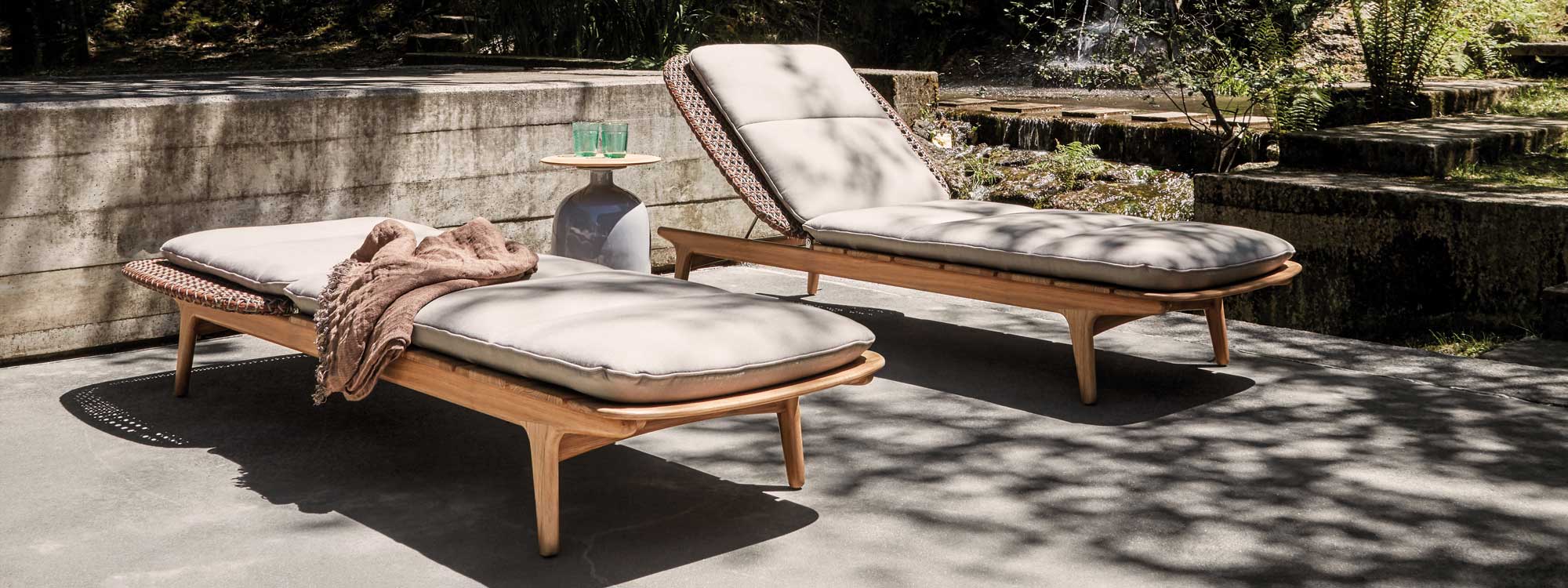 Image of pair of Gloster Kay adjustable teak & wicker sun loungers in sun & shade on terrace