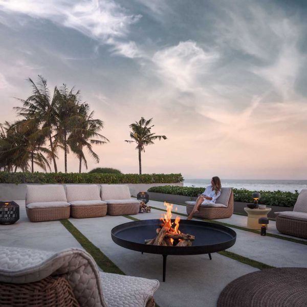 Image of Gloster freestanding fire bowl surrounded by Omada modern rattan garden sofas by Mark Gabbertas