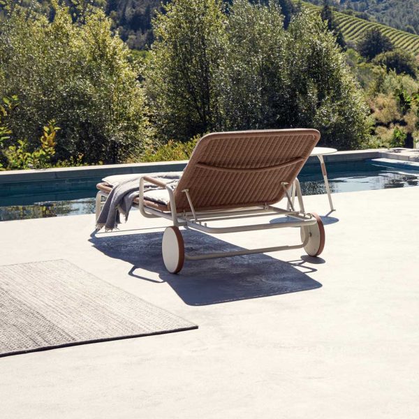 Image of Gloster Fresco contemporary sun lounger on sunny poolside with trees in the background