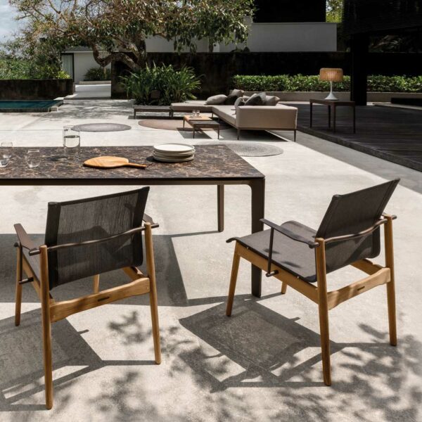 Image of Sway teak dining chairs and Carver garden table on sunny modern terrace, with Grid sofa by Gloster in the background