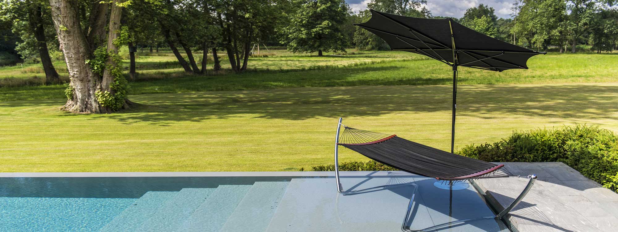 photo of Tuuci ocean master razor parasol in black by a pool with luxury hammock