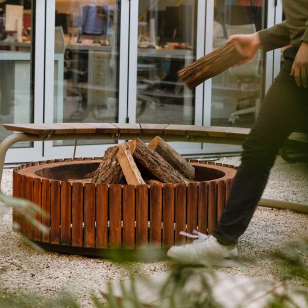 Image of man loading firewood into The Ring modern garden fire pit's fire bowl