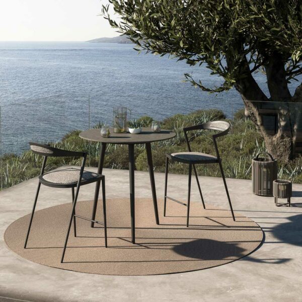 Image of Styletto minimalist outdoor bar stool and high bar table on circular outdoor carpet next to Ropy solar-powered lights