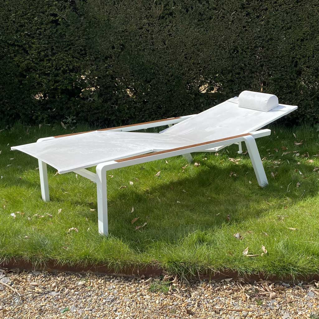 Image of white Royal Botania Alura 195T sun lounger on grass with yew hedge in the background