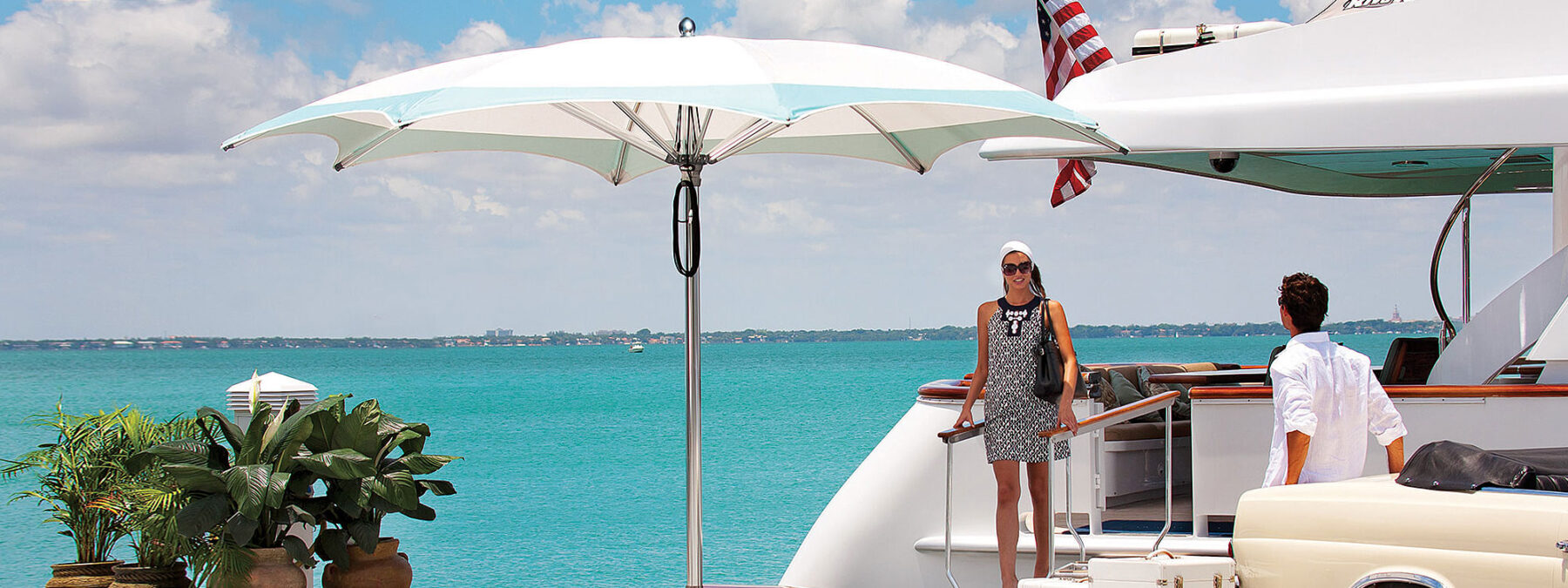 Image of woman disembarking from superyacht in sunshine, with Tuuci Ocean Master Max centre pole parasol with white canopy on quayside