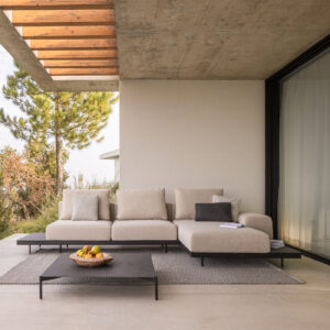 Image of Dongo chaise longue and sectional sofa shown on poured concrete terrace beneath cantilevered ceiling