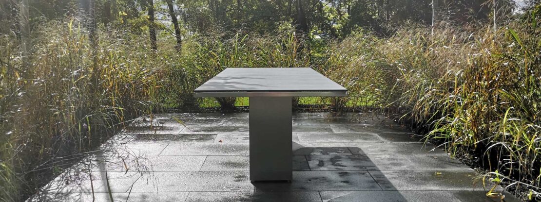 Image of Doble modern rectangular garden table surrounded by Miscanthus grasses