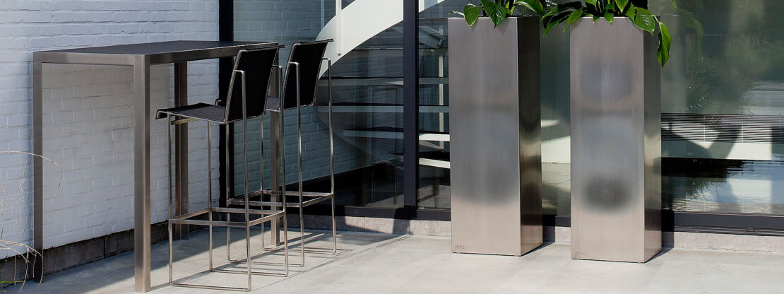Image of Nimio stainless steel bar table with black ceramic table top and Taburete bar stool with black Batyline seat & back by FueraDentro