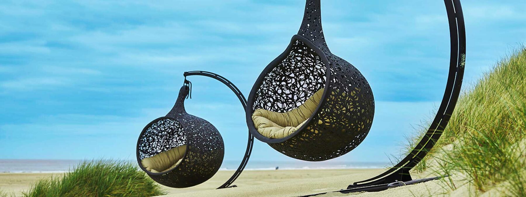 Image of Bios Hide and Bios Nest swing seats on stands amongst dunes on beach