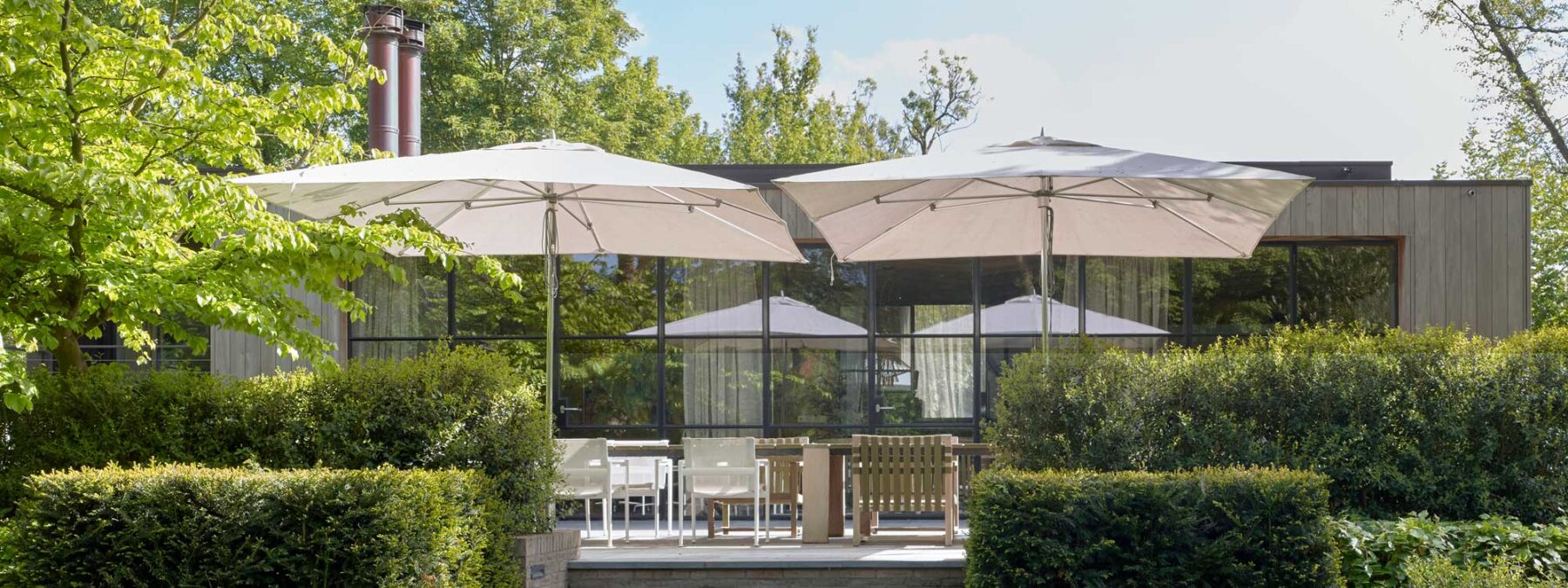 Image of white Tuuci Ocean Master mast parasols with polished titanium mast and ribs on terrace above modern garden furniture