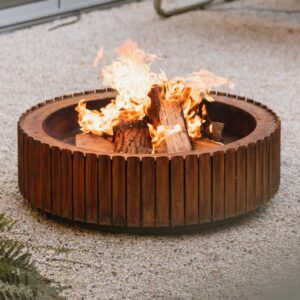 Image of flames dancing within Wunder The Ring modern corten fire pit, shown on gravel surface