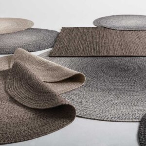Studio image of different coloured luxury garden carpets and rugs by Gloster laid over one another