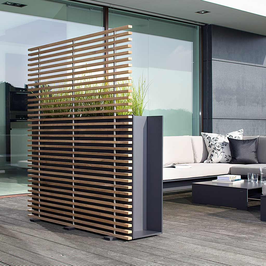 Image of rear view of Sotomon raised plant pot with trellis on terrace, with RIVA modern garden sofa and large glass windows in the background