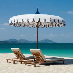 Image of Tuuci Ocean Master M1 Voilare Wunder parasol above a pair of Tuuci luxury sun loungers on a tropical beach