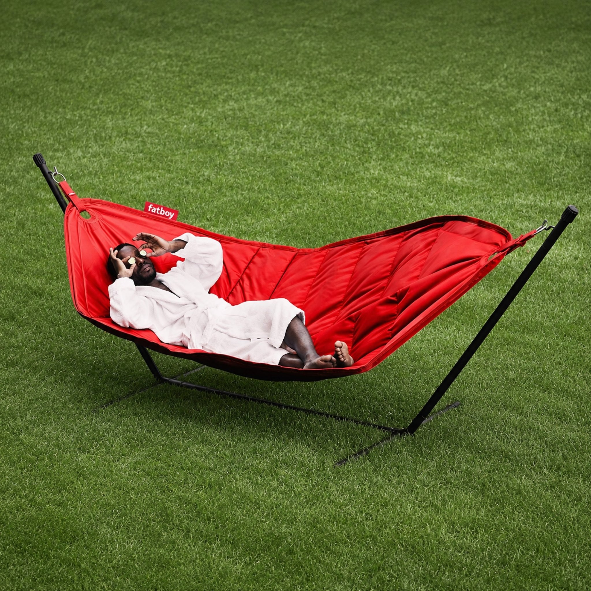Image of man in dressing gown lying down with slices of cucumber over his eyes in Fatboy Headdemock hammock