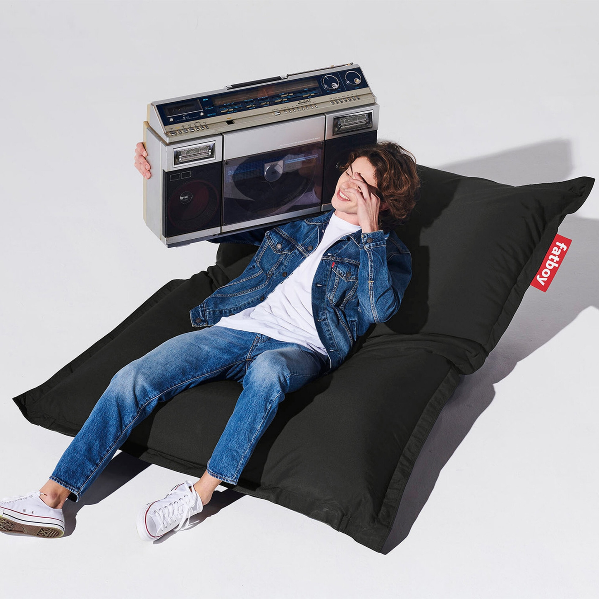 Image of youth lying back on Fatboy Original Outdoor beanbag with ghetto blaster